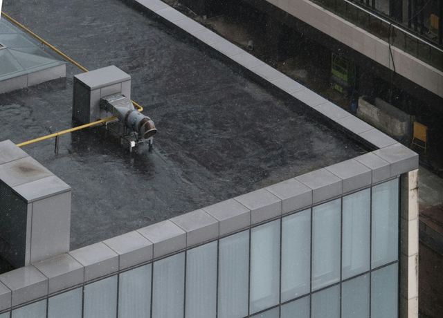 A dark membrane flat roof with a low parapet wall and a rooftop vent
