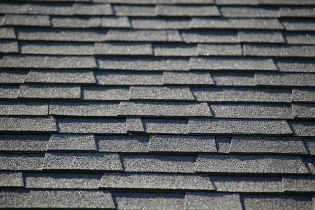 Close-up of gray three-tab asphalt shingles in even rows with crisp shadow lines