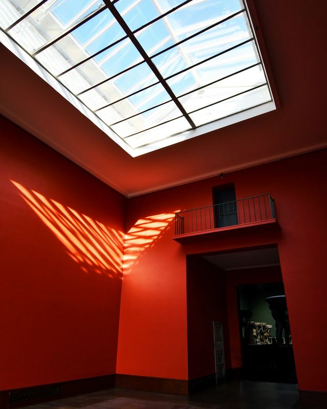 Daylight pouring through a large skylight into a room with deep red walls